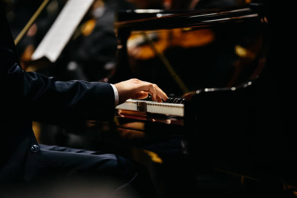 Pianist playing a piece on a grand piano at a concert, seen from the side